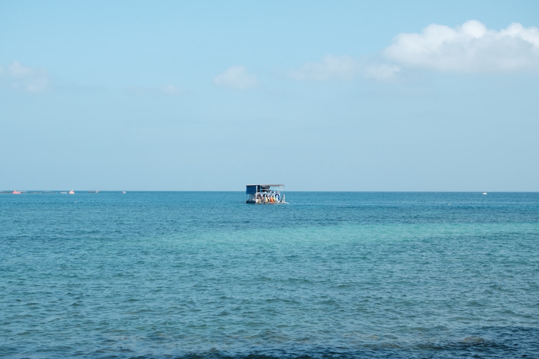 A small boat floats on the calm blue ocean.